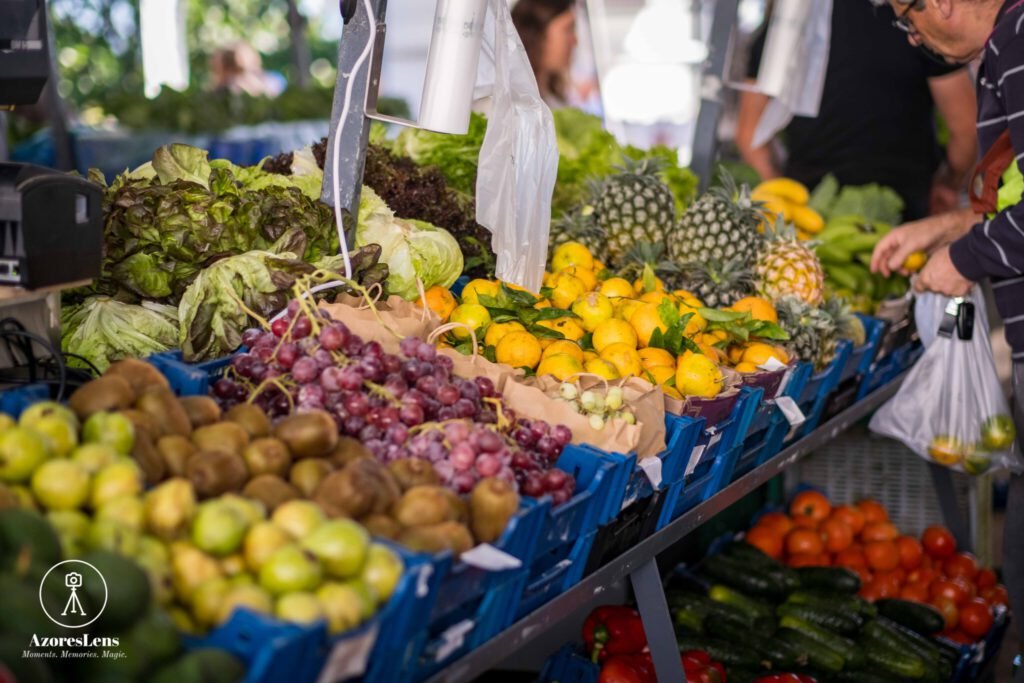 Vibrant scene at the weekly Azorean producers' market, showcasing locally grown and crafted goods. Colorful stalls filled with fresh fruits, vegetables, handmade crafts, and the bustling atmosphere of community connection.